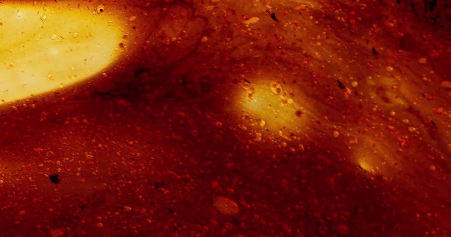 Bubbles move in a red and orange organic substance as it comes to life and colors blend