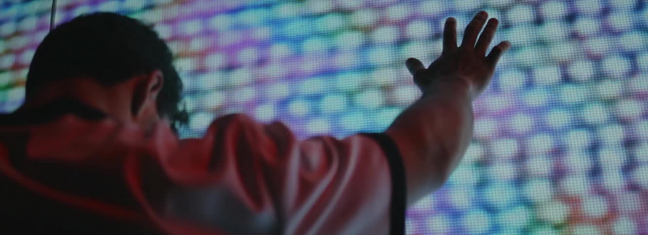 Young man touches a large video screen displaying chaotic images