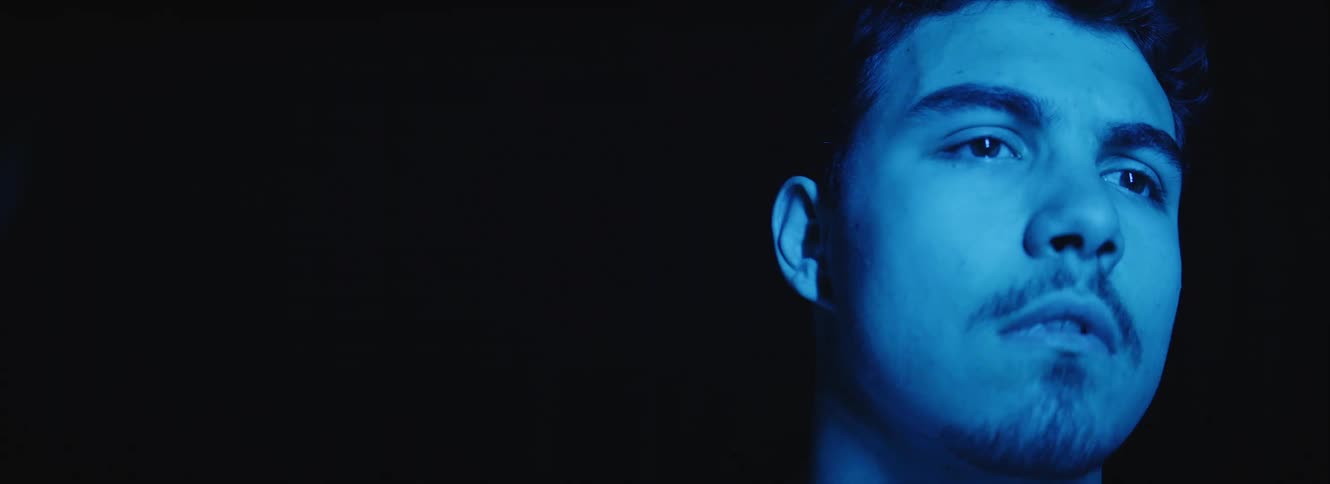 The strobe light is flashing on the mans face in the dark