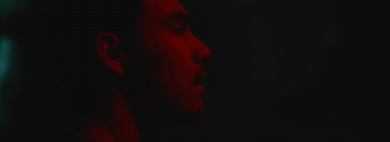 Man with white t shirt nears large screen touching and awing in dark room