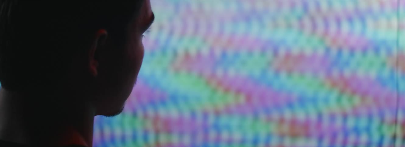 A man sits in front of a television with a fuzzy screen