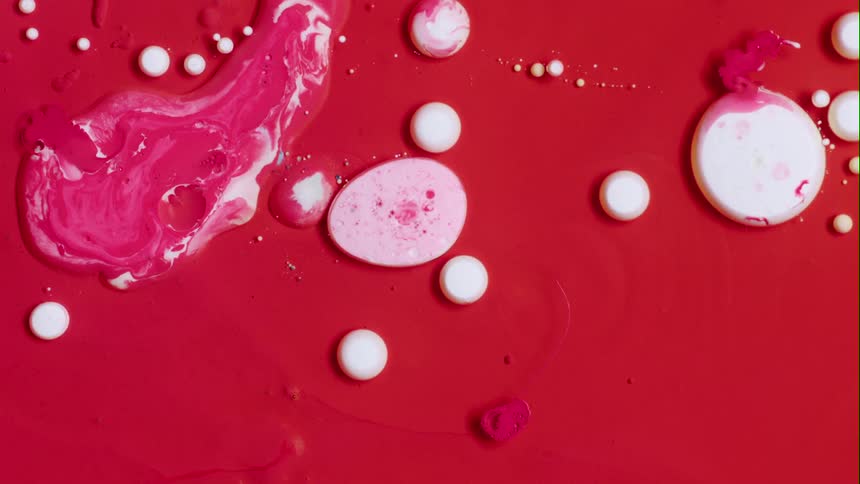 Splatters of white paint are squirted onto and combine with red paint