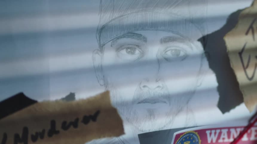 A police sketch of a wanted man is pinned to a bulletin board with notes