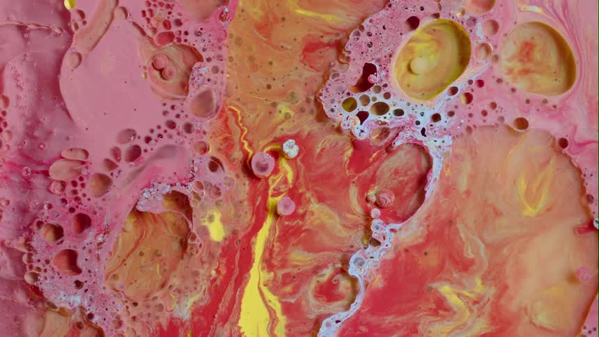 Pink and yellow paint combine together to create swirl patterns
