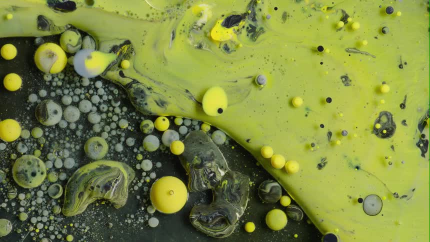 Yellow liquid flowing and creating bubbles against black and gray