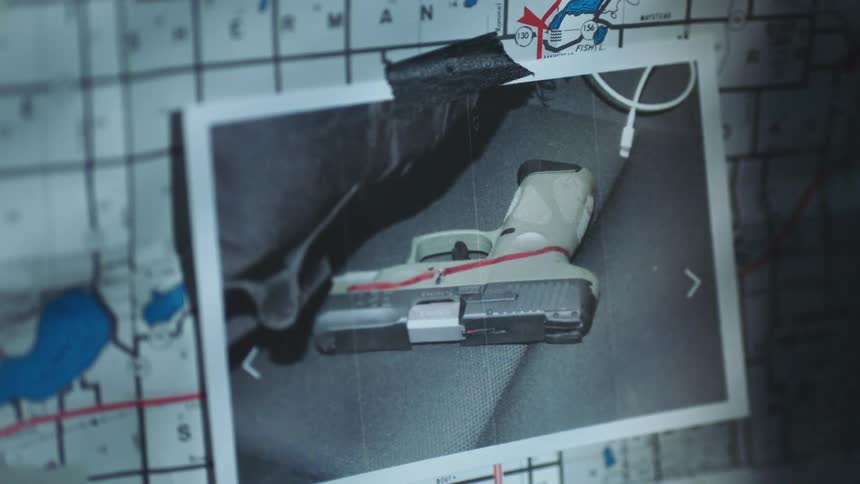 A photograph of a gun is taped on top of a map grid on a crime board