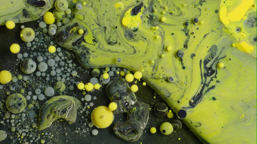 A living green substance with yellow scattered orbs is moving and blending with darker shades