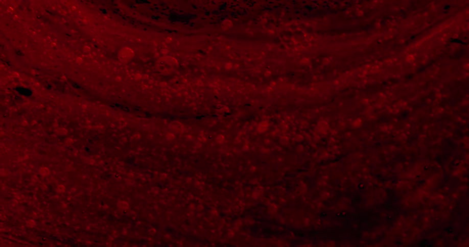 Red colored encrusted substance slowly flows in dim light