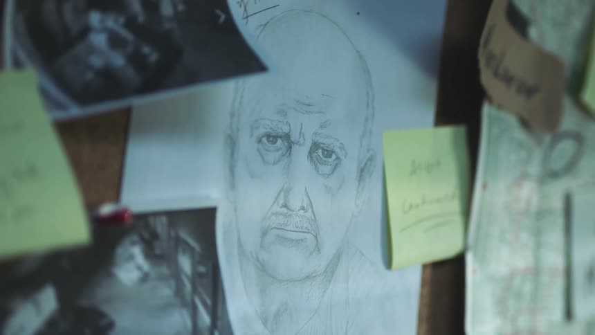 A sketch of an older mans face tacked to the center of a board surrounded by notes photos and clues