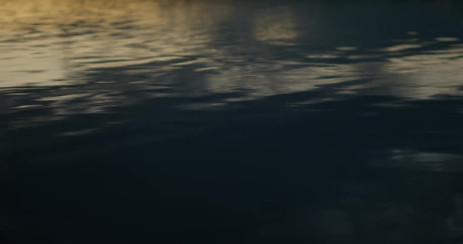 Flowing river water passes through light and shadow as it reflects the surroundings