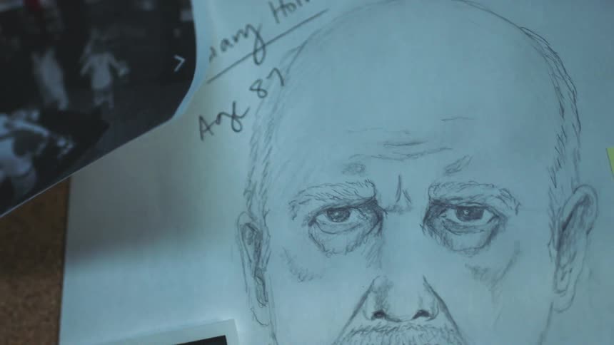 A sketch of a man and photographs are pinned to a bulletin board with a note