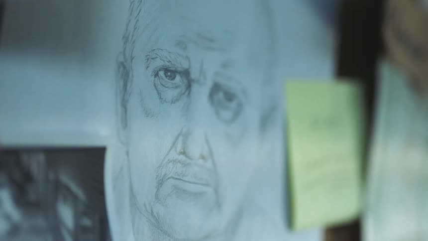 The sketch of a mans face tacked to a board along with notes and maps