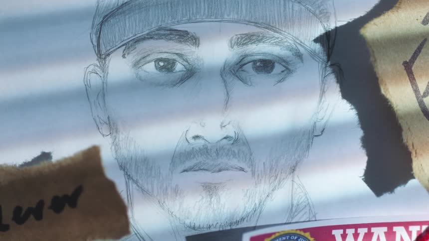 A suspect sketch on a board with a wanted poster and notes