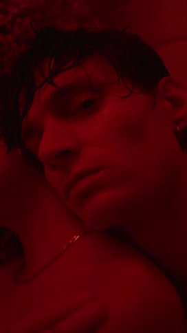 Man back hugs woman under colored lighting before closing his eyes