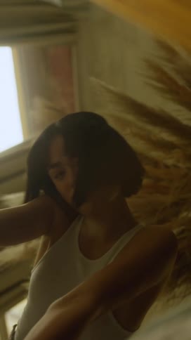 Womans hair is blown about as she poses near window