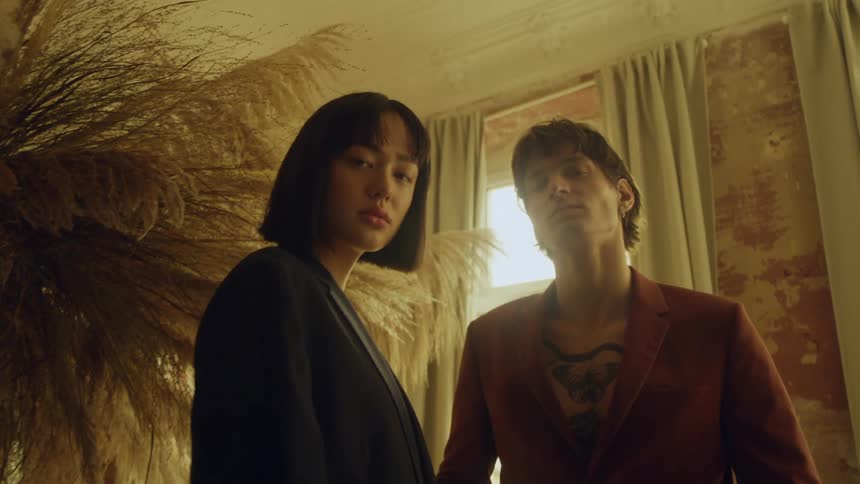 A man and woman stand inside a building and look ahead