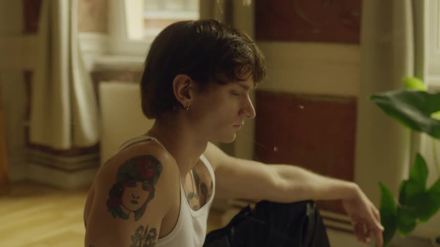 A sad looking man sits inside a house