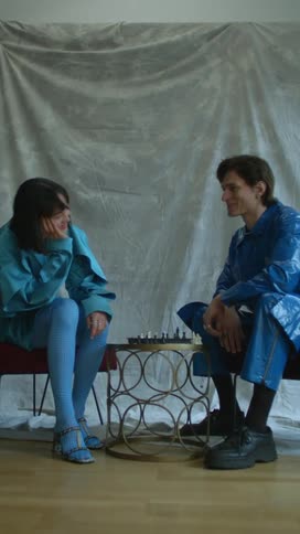 A woman and man laugh while playing chess