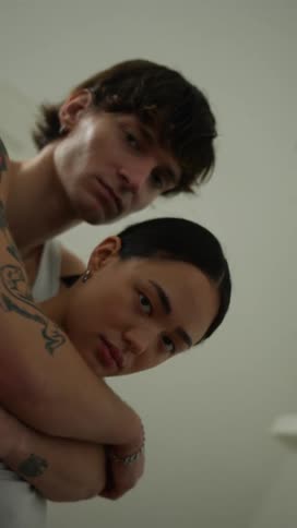 A man is standing behind his girlfriend and he has his arms around her