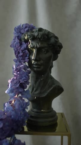 Flowers on a sculpture of a persons head breaking and falling