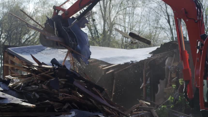 A backhoe works at tearing down a damaged building
