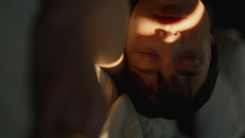 Strip of sunlight moves across womans face until it shines across her eyes and wakes her