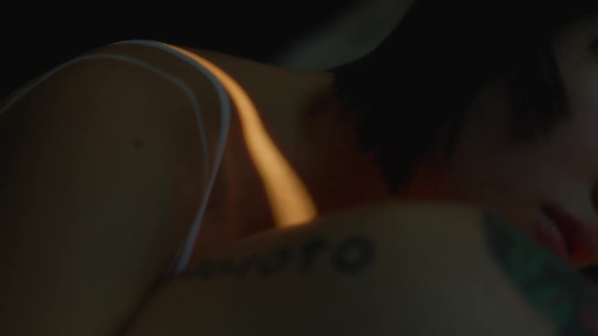 A sliver of light moves across the bodies of a couple lying in bed together and shines across the womans face