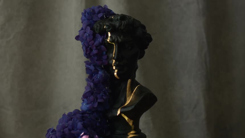A bust with flowers on it sits on a table