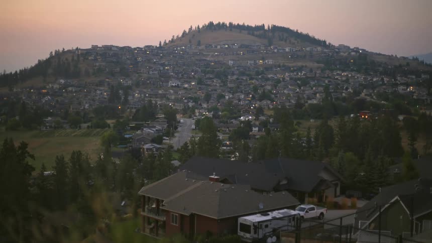 Homes built onto the slope of a hill with some lights glowing at dusk
