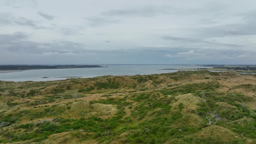 Hills border shore and water stretches to the misty horizon on an overcast day