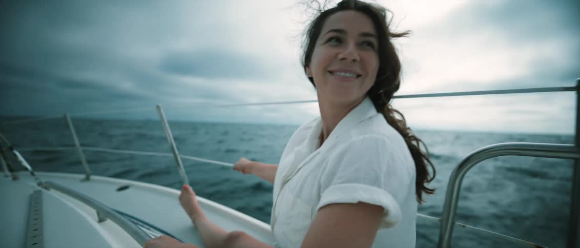 A woman laughs while riding a sailboat in the ocean