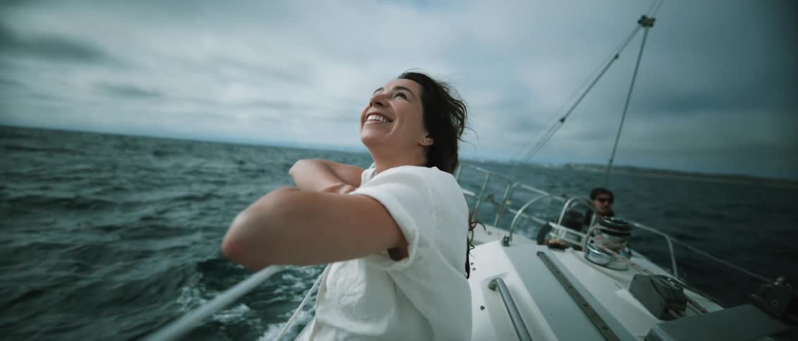 Woman sailing in ocean looks up at birds