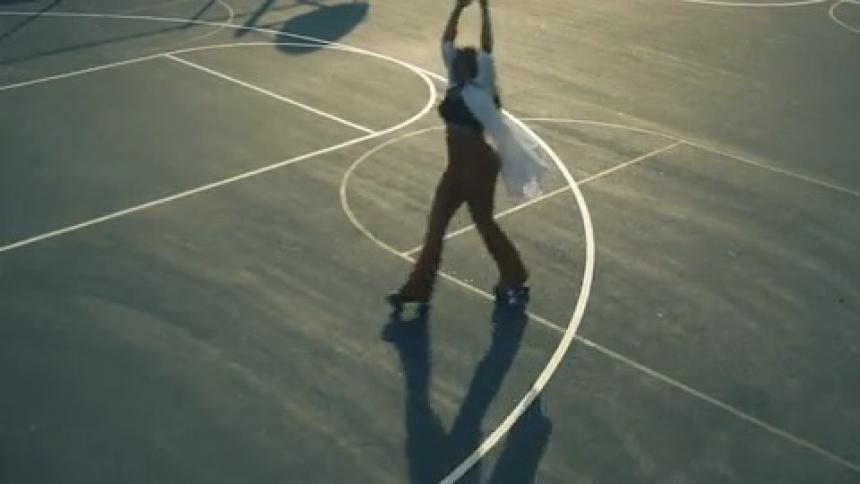 Young woman wearing a white shirt rollerskating on a basketball court