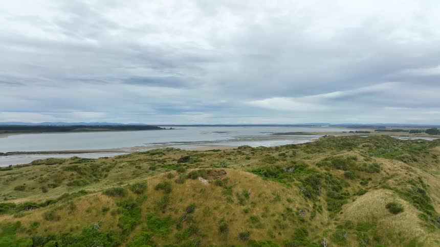 Aerial view of green hills overlooking coast on cloudy day