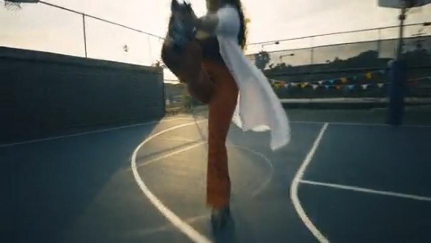 A woman roller skates past camera while doing a trick