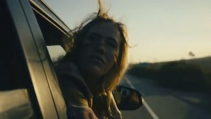 Woman hangs her head out of window as vehicle drives along highway