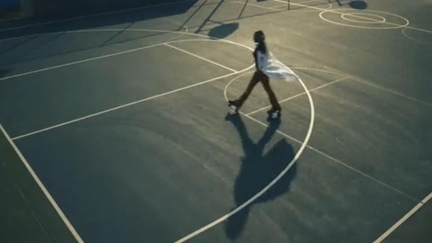 Woman wearing a white shirt roller skates across a basketball court