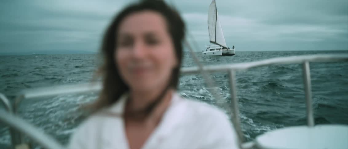 A woman sailing in the ocean looks back at a boat following her