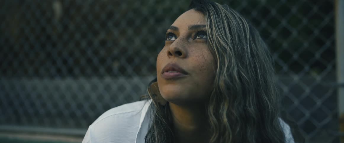 Woman on a basketball court looks up at birds