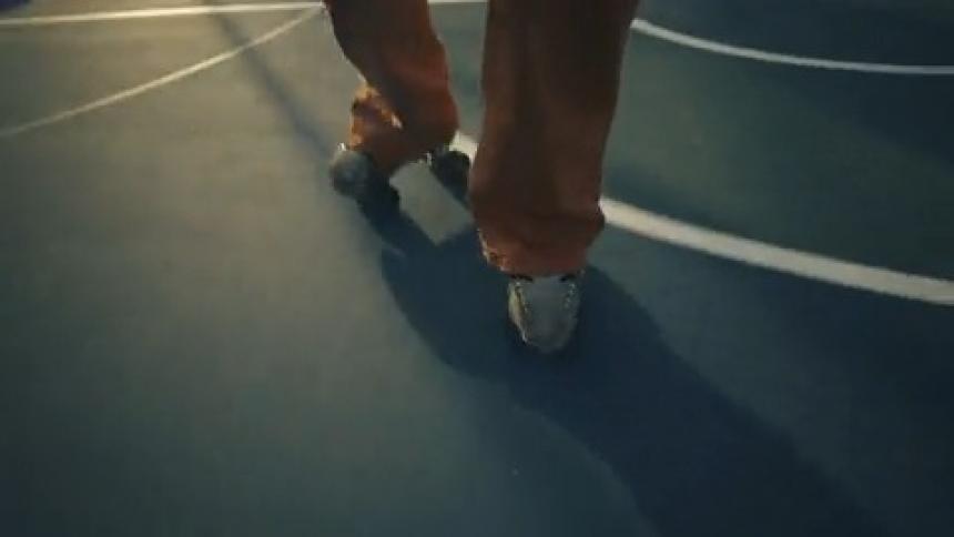 Female roller skater with orange pants roller skates on court surface
