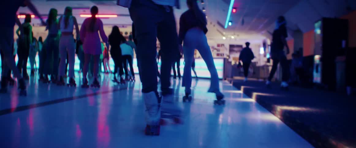 Man wearing roller skating on a rink under blue lights doing tricks