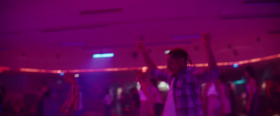 A man dancing and twirling on roller skates at a roller rink in the middle of other skaters