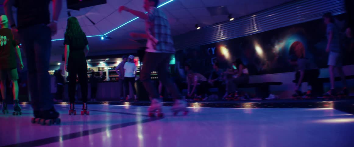 A man dancing and spinning through the crowd on roller skates in a roller rink