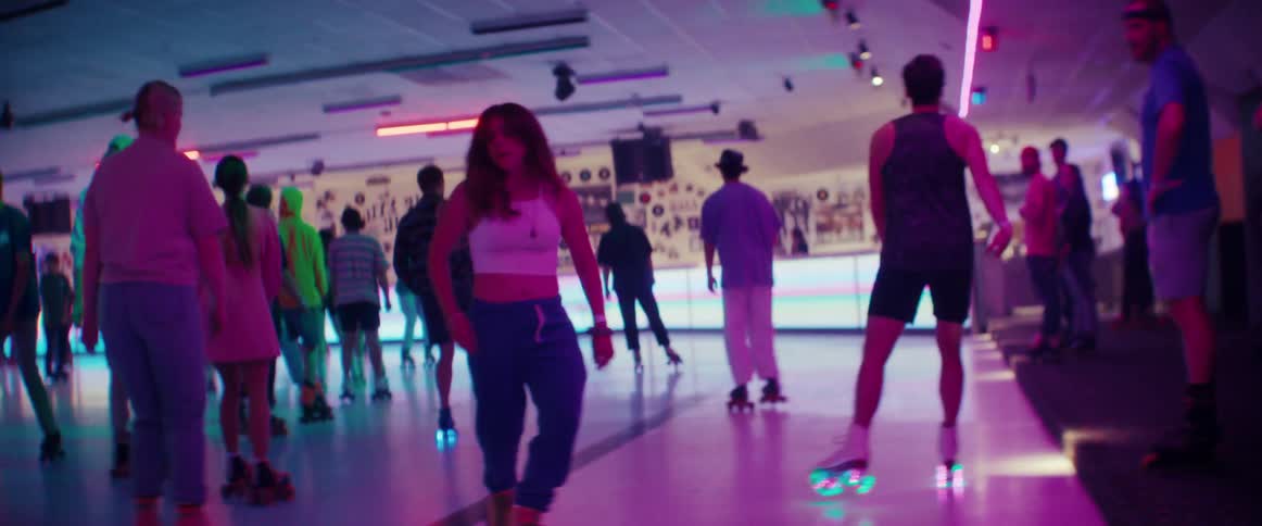 Woman roller dances while skating on a rink magenta and blue lights