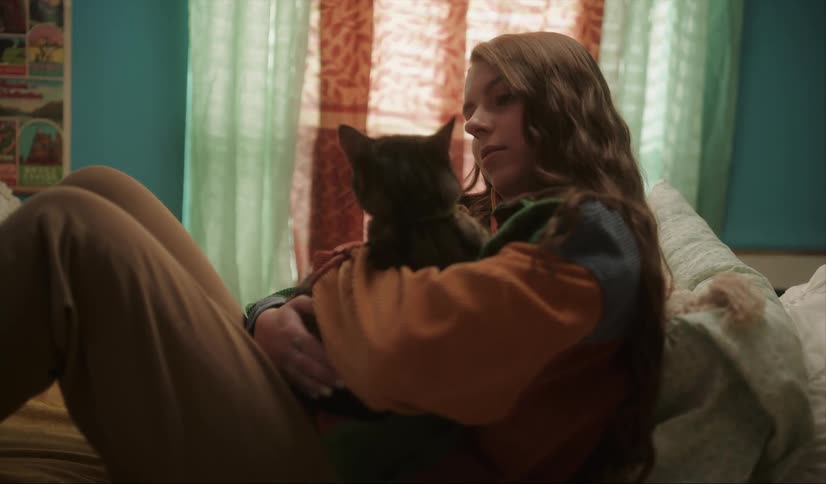 Relaxed young woman sitting in the bed hugs and pets her big cat
