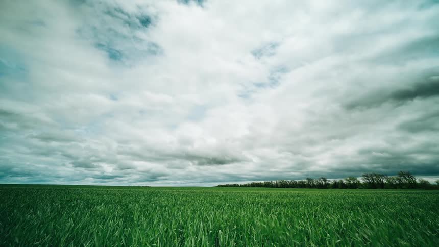 White clouds float over football field with green grass