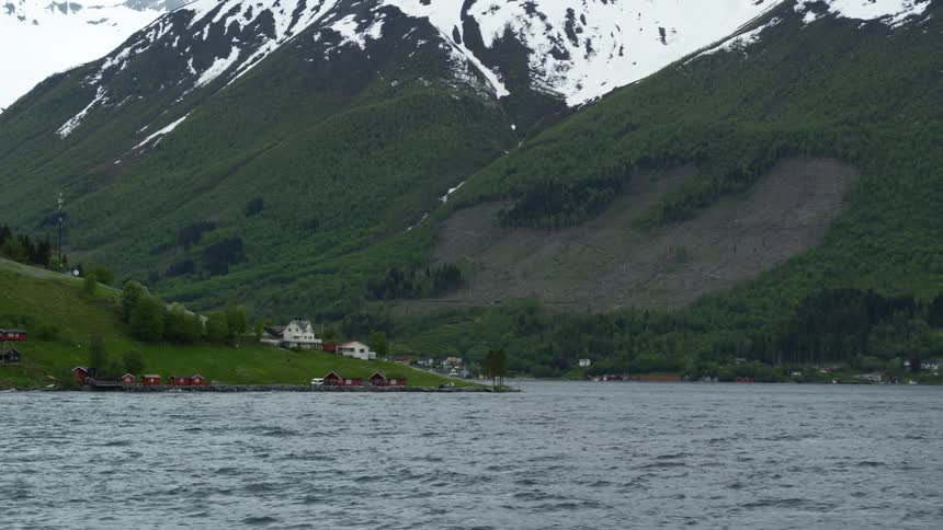 Water view of Norwegian village surrounded by snow capped mountains