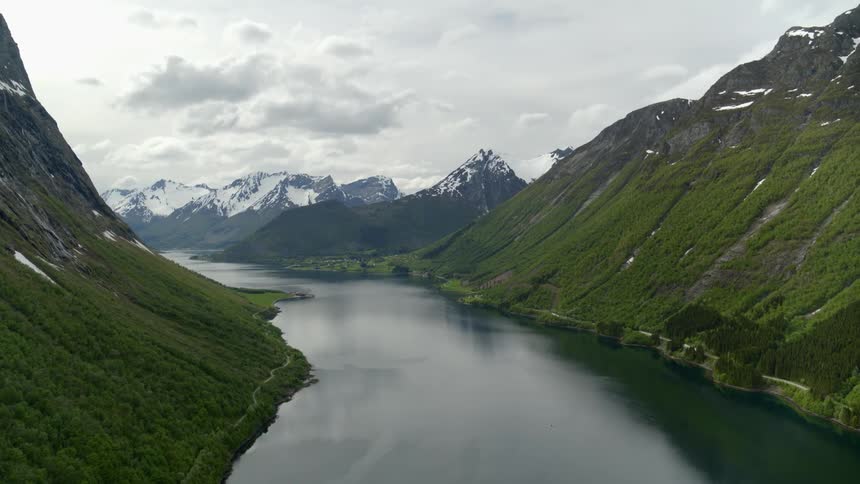 Aerial view of a Norwegian fjord with snow capped mountains in the distance