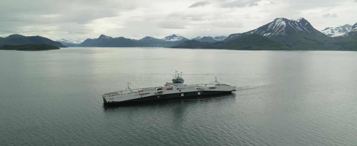 A passenger ferry in the norwegian waters near snow dusted mountains
