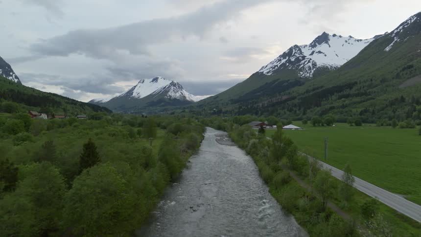 Aerial view of a river flowing through a rural area on a valley in the mountains at evening